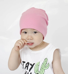 Close-up of a baby wearing a pink soft cotton knitted beanie hat on a white background