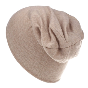 Close-up of beige cotton knit beanie showing fine ribbed texture and slouchy folds