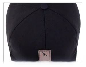 Close-up of black baseball cap showing reinforced top stitching and square leather patch