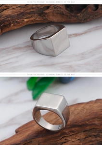 Macro shot of silver square signet ring showing polished surface on wood and marble