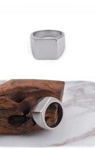 Macro view of polished square signet ring on wooden block with marble background