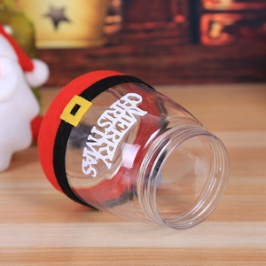 Festive transparent Christmas candy jar with red Santa belt design on a wooden surface
