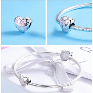Macro detail of S925 sterling silver heart charm with pink enamel paw prints and love engraving