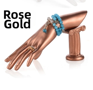 Vista de detalle del soporte de joyas mano rosa dorado con anillos sobre columna romana