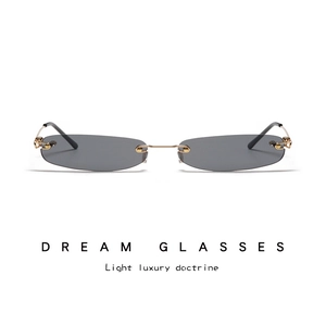 Close-up of rimless rectangular sunglasses with gold metal temples and dark gray lenses