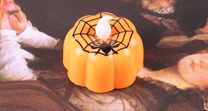 Macro detail of Halloween orange pumpkin LED candle with black spider web pattern
