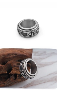Detail of retro stainless steel spinner ring with embossed Sanskrit symbols on wood surface