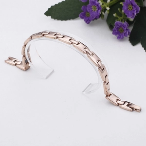 Rose gold magnetic therapy bracelet with H-shaped links on a transparent acrylic stand