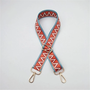 Close-up of ethnic woven bag strap with orange blue geometric patterns and gold metal buckles