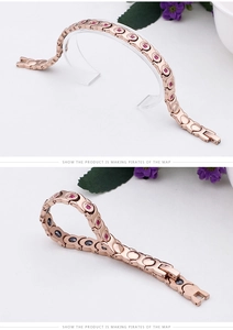 Detail of rose gold plated magnetic therapy bracelet with red crystals and magnets