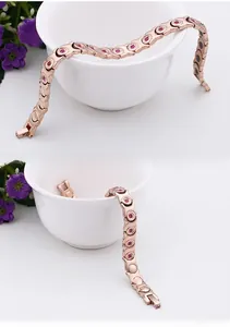 Close-up of rose gold bracelet featuring red crystal inlay and health magnets on the back