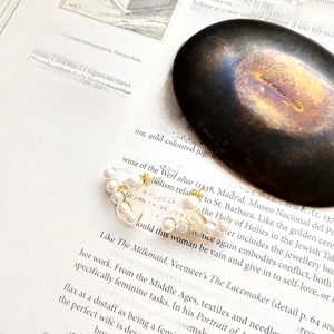 Close-up of elegant 925 sterling silver pearl arc stud earrings on vintage book page