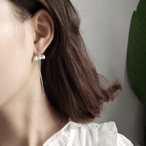 Close-up of long 925 silver threader earrings with three pearls on elegant female model