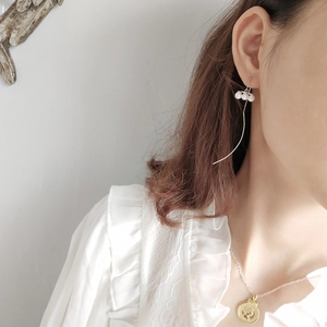 Close-up of elegant pearl drop threader earrings worn by a model in a minimalist setting