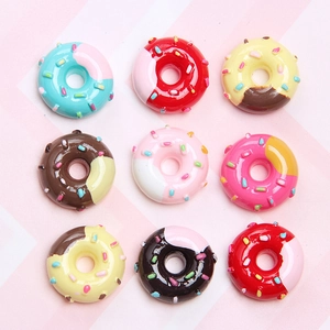 Flat lay of nine colorful miniature resin donuts with sprinkles on striped background