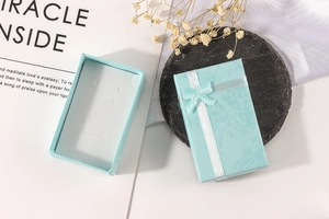 Detail of light blue jewelry boxes with white ribbons and sponge inserts for necklaces