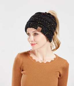 Detail of black knit beanie with colorful speckles and functional ponytail opening
