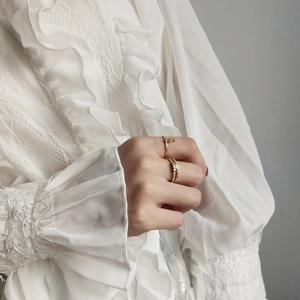 Close-up of gold layered rings with marquise crystals worn on a hand with lace sleeve