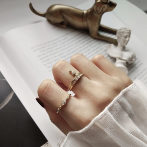 Close-up of minimalist gold layered rings with cubic zirconia on a female finger