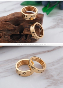 Close-up of gold titanium couple rings featuring black engraved gender symbols and lines