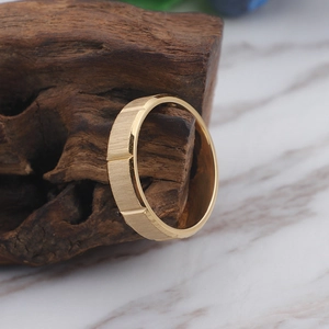 Bague de couple en acier inoxydable doré brossé posée sur un bloc de bois foncé