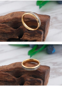 Detail of two-tone titanium steel ring with brushed center and gold edges on wood