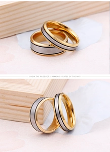Detail of couple rings featuring silver brushed finish and gold edges on wood background
