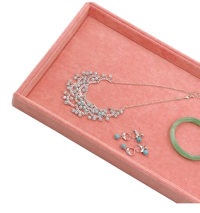 Detailed view of pink velvet jewelry tray displaying necklaces and earrings in soft light