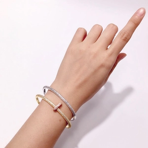 Close-up of gold and silver pavé-set bangles featuring a T-shaped sparkling diamond design