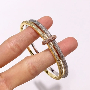 Detail van de driekleurige goud en zilveren dubbele ringarmband met pavé diamant