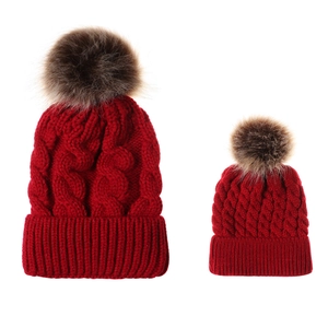 Matching red cable knit beanie set for parent and child with faux fur pom-poms