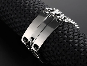 Macro detail of polished stainless steel chain bracelet with blank metal plates on a black stand