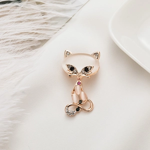Detailed close-up of a golden cat brooch with pink opal and sparkling crystals