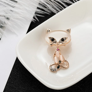 Elegant rose gold cat brooch with pink opal and rhinestones on a white ceramic plate