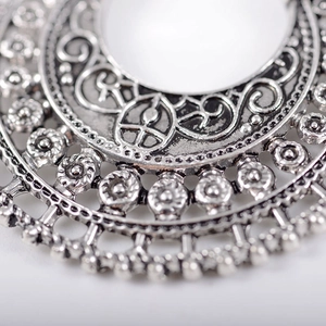 Macro shot of bohemian vintage hollow floral patterns and silver alloy earring textures
