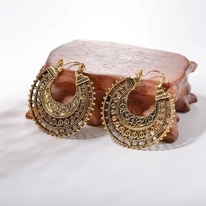 Bohemian vintage hollow carved hoop earrings in antique gold finish on wooden stand