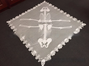Detailed macro of white lace Halloween shawl featuring skeletal patterns and skulls