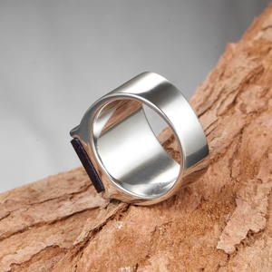 Vue macro de la bague en titane argenté avec grès bleu sur une écorce d'arbre