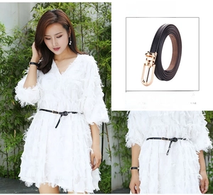 Detail of slim black leather belt with golden pin buckle on a white dress