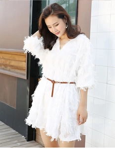 Detail of slim brown leather belt with gold pin buckle on a white tassel skirt