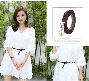 Detail of dark coffee leather belt with gold buckle styled on a white tassel dress