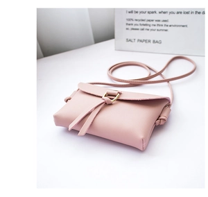 Detailed shot of pink mini crossbody bag with gold ring buckle on a white table