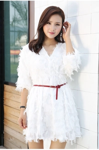 Detail of a thin red leather belt accentuating a white fringed fabric dress for women