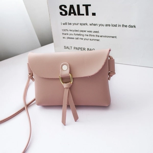 Pink mini crossbody phone bag with gold metal ring and tassel on a white platform
