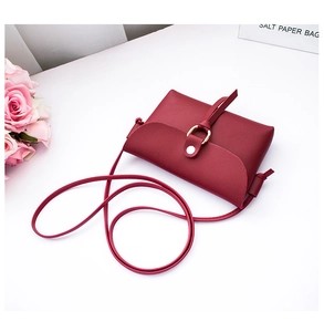 Detail of wine red mini crossbody bag with golden ring buckle and textured PU leather