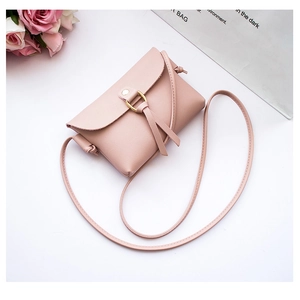 Detail of pink mini crossbody bag featuring a golden ring closure and stylish tassel