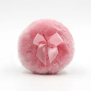 Soft pink plush baby powder puff with a satin bow knot on a clean white background