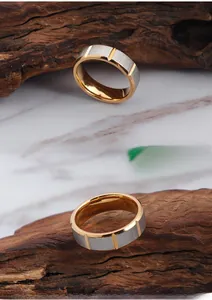 Macro detail of dual-tone brushed titanium steel ring with gold grooves on wood