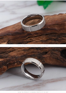 Detail of silver brushed titanium ring with geometric grooves on a dark marble surface