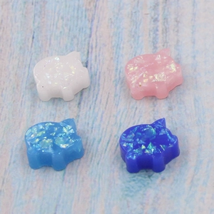 Macro view of colorful opal pig charms with glitter in white, pink, and blue shades